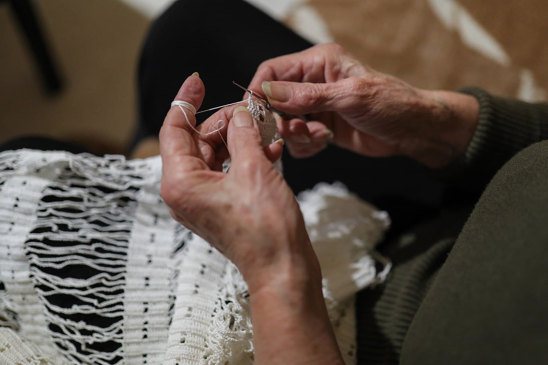 Mani di una signora anziana che lavora all'uncinetto